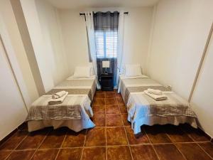 Duas camas num quarto com piso em azulejo e uma janela. em Vista Marina - El Medano Beach em El Médano