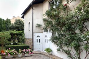 una casa con una puerta blanca y algunas flores en Modern&Cozy Bosnian house with GARDEN+FREE parking, en Sarajevo