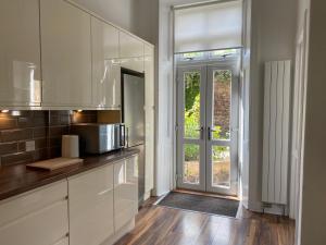 una cucina con armadi bianchi e una porta in vetro di Lovely main door 2 bed apartment a Edimburgo