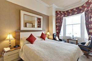 a bedroom with a large bed and a mirror at Lauriston & Lawton Court Hotel in Llandudno