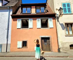 a woman in a dress standing in front of a building at Home La Petite Porte - Petite Venise - Colmar in Colmar
