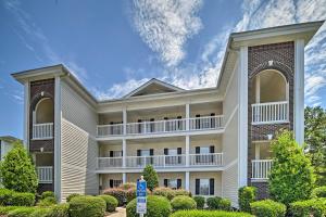 a large building with balconies and bushes at Myrtle Beach Condo with Screened Porch and Pool Access in Myrtle Beach