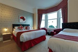 a hotel room with two beds and a window at Lauriston & Lawton Court Hotel in Llandudno