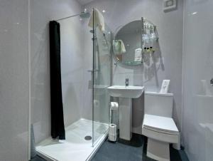 a bathroom with a shower and a toilet and a sink at Lauriston & Lawton Court Hotel in Llandudno