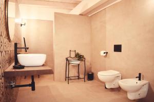 y baño con aseo blanco y lavamanos. en Il Casale dei Calanchi, en Aliano