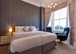 a bedroom with a bed and a chair and a window at Lauriston & Lawton Court Hotel in Llandudno