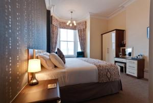 a bedroom with a bed and a desk and a window at Lauriston & Lawton Court Hotel in Llandudno