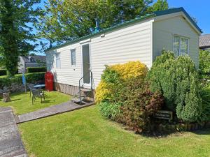 a white house with a yard with a chair and bushes at Rivermead Holidays in Saint Breward
