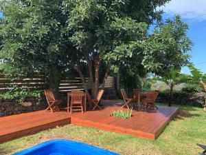 una terraza de madera con sillas y una mesa bajo un árbol en Appartement 2 avec wifi, en Ravine des Cabris