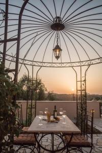 una mesa con copas de vino y una sombrilla en el patio en Achillion Casa Conti 1840, en Gastouri