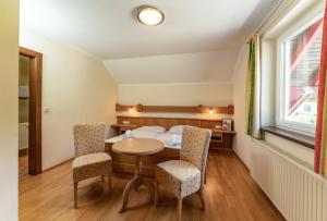 a room with a table and chairs and a bed at Landhaus Metzgerstubn in Sankt Martin