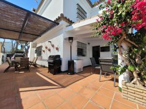 an outdoor patio with chairs and tables and flowers at Chalet con piscina a 300 m del mar in Chiclana de la Frontera