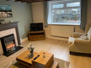 a living room with a fireplace and a tv at Miners cottage(1840)Nr. Brecon,Tower Zip & Bike Pk in Aberdare