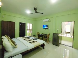 a bedroom with a large bed and a table in it at The Narrow Way Edward Guest House in Candolim