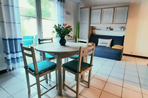 a dining room table with chairs and a vase with flowers at Délicieux moment de détente au coeur de Saint Martin de Ré in Saint-Martin-de-Ré