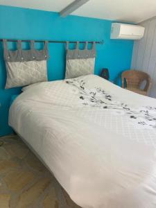 a large white bed in a room with a blue wall at Le clos des olivettes in Sainte-Croix-de-Quintillargues