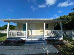 a small white house with a white fence at Maria's Los Cirhuelos in Homestead