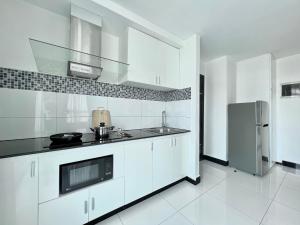 a white kitchen with a sink and a refrigerator at PTH Residence in Phnom Penh