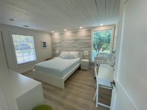 a bedroom with a bed and a desk and two windows at Maria's Los Cirhuelos in Homestead