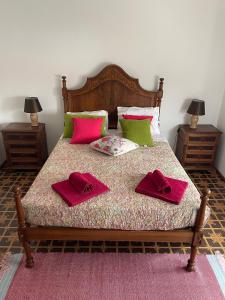 Una cama con dos toallas rojas encima. en Monte de Stª Margarida, en Montemor-o-Novo