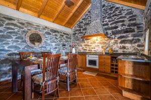 a kitchen with a table and chairs and a stone wall at Rainbow Cottage by Madeira Sun Travel in Ponta do Pargo