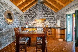 a kitchen with a table and chairs and a stone wall at Rainbow Cottage by Madeira Sun Travel in Ponta do Pargo