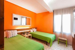 two beds in a room with orange and green at Hostal Collsacabra in L’ Esquirol