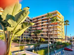 duży budynek apartamentowy z palmami przed nim w obiekcie APARTAMENTO 1ª LINEA PLAYA GARAJE PISCINAS TERRAZA w mieście Torremolinos