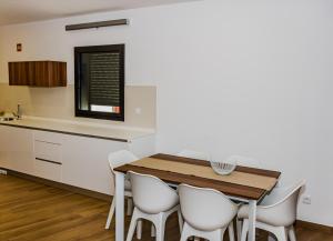 a kitchen with a wooden table and white chairs at Casas de Campo Curral Grande - By Cimo da Quinta in Miranda do Douro