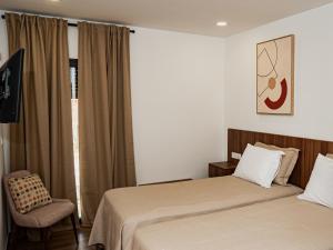 a hotel room with two beds and a chair at Casas de Campo Curral Grande - By Cimo da Quinta in Pena Branca +22 photos