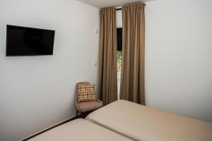 a bedroom with a bed and a chair and a television at Casas de Campo Curral Grande - By Cimo da Quinta in Pena Branca