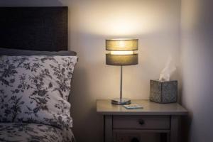 a lamp on a night stand next to a bed at Ideal Couples base for exploring the Island in Shiskine