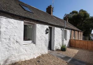a white cottage with a window and a fence at Ideal Couples base for exploring the Island in Shiskine