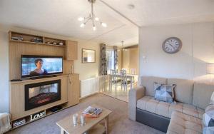 a living room with a couch and a tv at HV66 - 3 Bedrooms Indoor Pool Loch Views Fishing Golf Riding Shooting Water Sports 15 Mins Drive To Beaches PASSES NOT INCLUDED Most Activities Will Not Be Available Out Of Season Please Check Before Booking in Newton Stewart