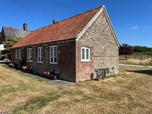 フルームにあるHeath House Farmのレンガ造りの小さな建物で、正面にベンチがあります。