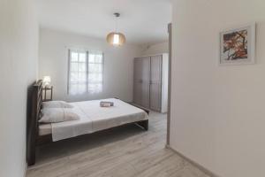 a white bedroom with a bed and a window at appartement 1 avec wifi in Ravine des Cabris