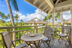 a table and chairs on a porch with palm trees at Koolkondo Luxury Designer Condo in Koloa