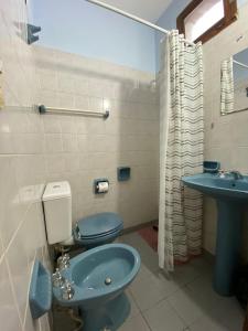 a bathroom with a blue toilet and a sink at MAKTUB HOSTERIA in El Bolsón