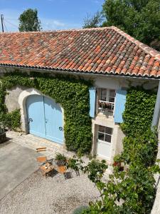 ein mit Efeu bewachsenes Haus mit einer blauen Garage in der Unterkunft Le logis de Lasteyrie in La Rochebeaucourt-et-Argentine