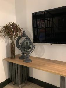 un reloj sentado en un estante junto a una TV en Studio aconchegante em Barra Mansa en Barra Mansa