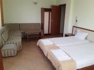 a hotel room with two beds and a couch at Kostovi Primorsko in Primorsko