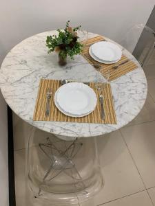 una mesa con dos platos y un jarrón con flores. en Studio aconchegante em Barra Mansa en Barra Mansa
