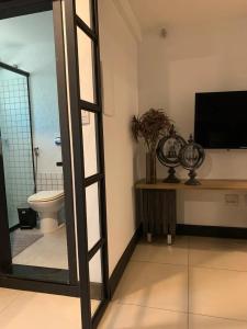 a bathroom with a toilet and a television in a room at Studio aconchegante em Barra Mansa in Barra Mansa