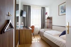 a hotel room with a bed and a desk at Hotel Aurbacher Hof GmbH in Munich