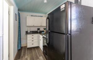 una cocina con nevera de acero inoxidable y armarios blancos en Bungalow 1 minute from the beach Suite #3, en Englewood