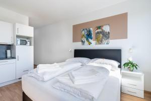 een wit bed met witte lakens en kussens bij FeelGood Apartments LakeLiving inklusive Garagenplatz in Wenen