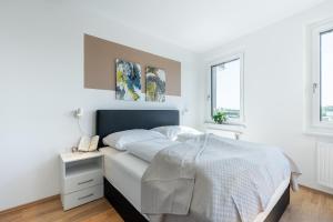 een witte slaapkamer met een groot bed en 2 ramen bij FeelGood Apartments LakeLiving inklusive Garagenplatz in Wenen