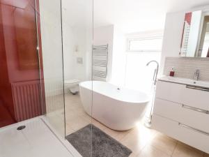 a white bathroom with a tub and a glass shower at The Old Tywyn Post Office in Conwy +36 photos