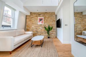 a living room with a white couch and a brick wall at Be London - The Covent Garden Residences in London