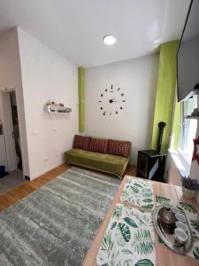 a living room with a couch and a clock on the wall at Green Oasis in Bjelašnica